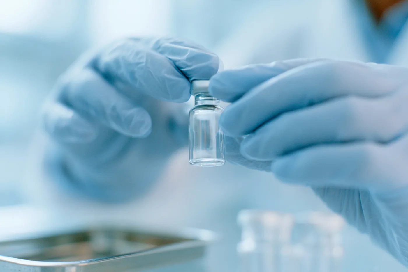 Pharmacist in gloves inspecting a compounded GLP-1 vial